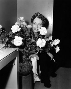 Gloria Swanson taking a cigarette break, with flowers, on the set of Sunset Blvd